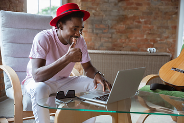 Image showing African-american man during videocall with his band sitting at home, musicians during quarantine and insulation