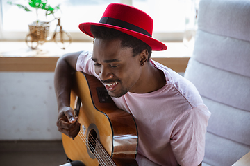 Image showing African-american musician playing guitar during online concert at home isolated and quarantined, impressive improvising