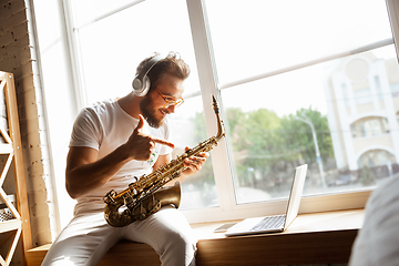 Image showing Caucasian musician playing saxophone during online concert at home isolated and quarantined, impressive improvising