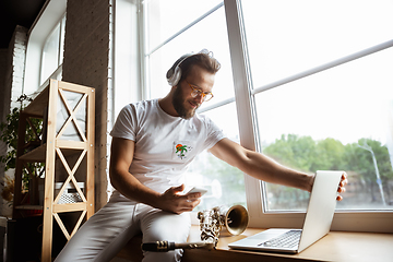 Image showing Caucasian musician preparing for concert at home isolated and quarantined, impressive improvising with band connected online