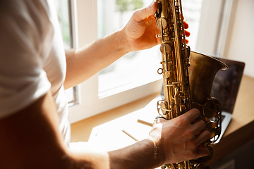 Image showing Caucasian musician playing saxophone during concert at home isolated and quarantined, impressive improvising with band connected online