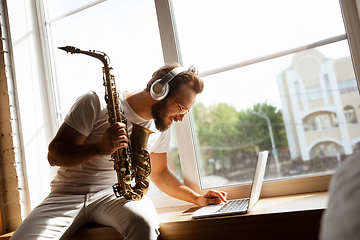 Image showing Caucasian musician playing saxophone during online concert at home isolated and quarantined, impressive improvising