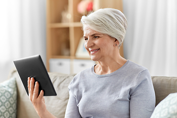 Image showing happy senior woman with tablet pc at home