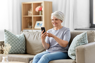 Image showing happy senior woman with smartphone at home