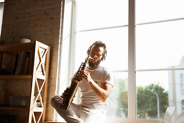 Image showing Caucasian musician playing saxophone during online concert at home isolated and quarantined, impressive improvising