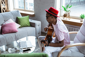 Image showing African-american musician playing guitar during online concert at home isolated and quarantined, impressive improvising