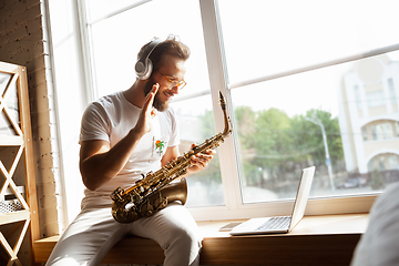 Image showing Caucasian musician playing saxophone during online concert at home isolated and quarantined, impressive improvising