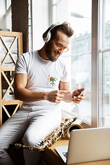 Image showing Caucasian musician preparing for concert at home isolated and quarantined, impressive improvising with band connected online