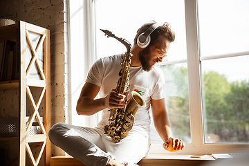 Image showing Caucasian musician playing saxophone during online concert at home isolated and quarantined, impressive improvising