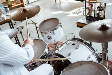 Image showing Close up of caucasian musician playing drumms during online concert with the band at home isolated and attented, smiling, cheerful