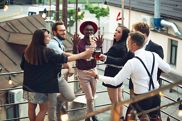 Image showing Multiethnic group of people celebrating, look happy, have corporate party at office or bar