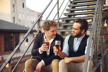 Image showing Two men talking, celebrating, look happy, have corporate party at office or bar