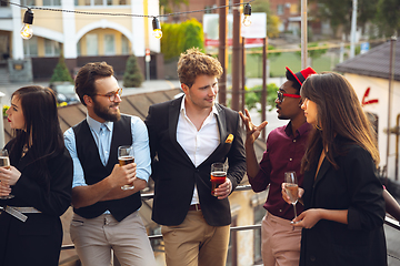 Image showing Multiethnic group of people celebrating, look happy, have corporate party at office or bar