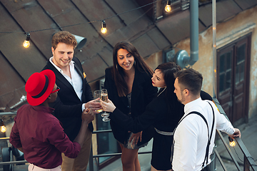 Image showing Corporate celebrating in the warm light of the lamps in summer evening, young friends, colleagues look happy, talk, have fun