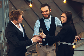 Image showing Corporate celebrating in the warm light of the lamps in summer evening, young friends, colleagues look happy, talk, have fun