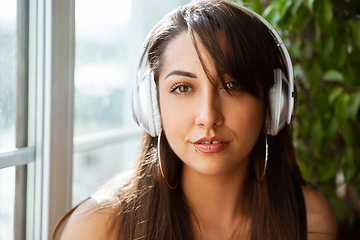 Image showing Close up of beautiful caucasian woman in wireless headphones listening to music, calm and attractive