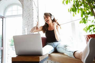 Image showing Caucasian female singer during online concert at home insulated and quarantined, cheerful and happy, singing live, performing