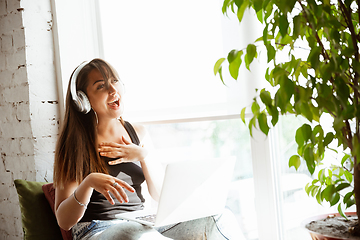 Image showing Caucasian female singer during online concert at home insulated and quarantined, cheerful and happy, singing live, performing