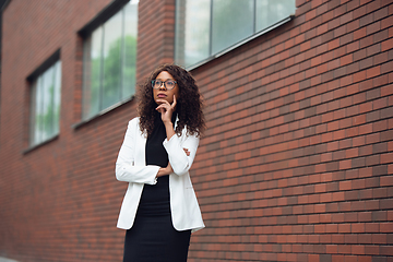 Image showing Beautiful african-american well-dressed businesswoman looks confident and busy, successful