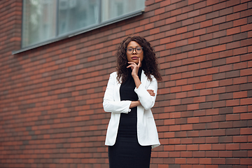 Image showing Beautiful african-american well-dressed businesswoman looks confident and busy, successful