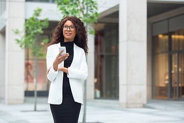 Image showing Beautiful african-american well-dressed businesswoman looks confident and busy, successful