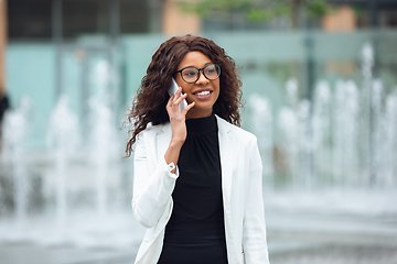 Image showing Beautiful african-american well-dressed businesswoman looks confident and busy, successful