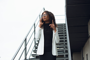 Image showing Beautiful african-american well-dressed businesswoman looks confident and busy, successful