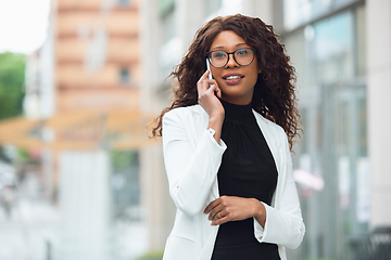 Image showing Beautiful african-american well-dressed businesswoman looks confident and busy, successful