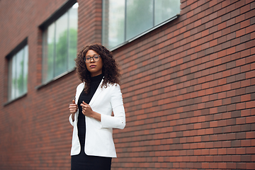 Image showing Beautiful african-american well-dressed businesswoman looks confident and busy, successful