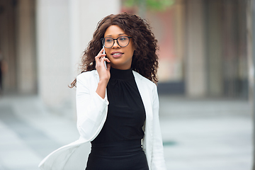 Image showing Beautiful african-american well-dressed businesswoman looks confident and busy, successful