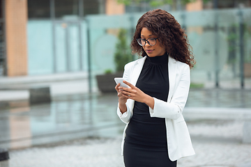 Image showing Beautiful african-american well-dressed businesswoman looks confident and busy, successful