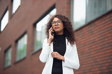 Image showing Beautiful african-american well-dressed businesswoman looks confident and busy, successful