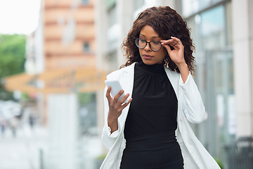 Image showing Beautiful african-american well-dressed businesswoman looks confident and busy, successful