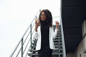 Image showing Beautiful african-american well-dressed businesswoman looks confident and busy, successful