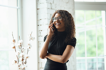 Image showing Beautiful african-american well-dressed businesswoman looks confident and busy, successful