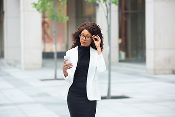 Image showing Beautiful african-american well-dressed businesswoman looks confident and busy, successful