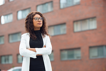 Image showing Beautiful african-american well-dressed businesswoman looks confident and busy, successful