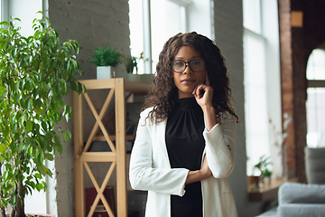 Image showing Beautiful african-american well-dressed businesswoman looks confident and busy, successful