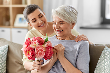 Image showing adult daughter giving flowers to old mother