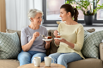 Image showing old mother and adult daughter eating cake at home