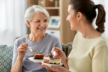 Image showing old mother and adult daughter eating cake at home