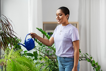 Image showing african american woman watering plants at home