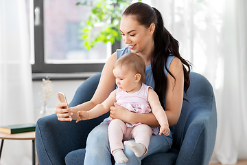 Image showing happy mother and baby with smartphone at home