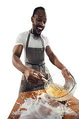 Image showing Amazing african-american man preparing unbelievable food with close up action, details and bright emotions, professional cook. Preparing omelet, mixing eggs with splashing milk