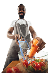 Image showing Amazing african-american man preparing unbelievable food with close up action, details and bright emotions, professional cook. Cutting carrot to salad