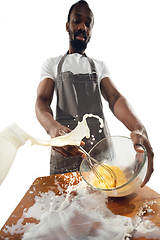 Image showing Amazing african-american man preparing unbelievable food with close up action, details and bright emotions, professional cook. Preparing omelet, mixing eggs with splashing milk
