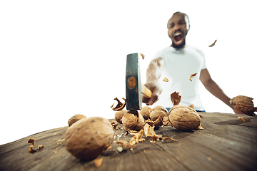 Image showing Amazing african-american man preparing unbelievable food with close up action, details and bright emotions, professional cook. Cracking nuts