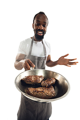 Image showing Amazing african-american man preparing unbelievable food with close up action, details and bright emotions, professional cook. Preparing fried meat, steakes