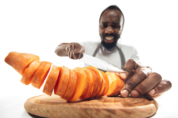 Image showing Amazing african-american man preparing unbelievable food with close up action, details and bright emotions, professional cook. Cutting carrot on the fly