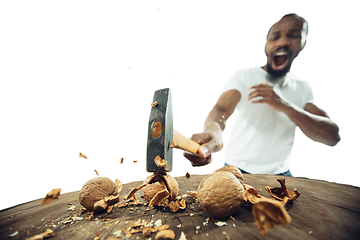 Image showing Amazing african-american man preparing unbelievable food with close up action, details and bright emotions, professional cook. Cracking nuts